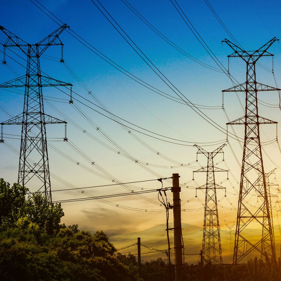 Sun setting behind the silhouette of electricity pylons